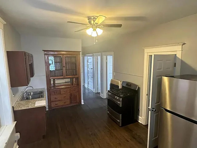 a kitchen with granite countertop a refrigerator cabinets and wooden floor