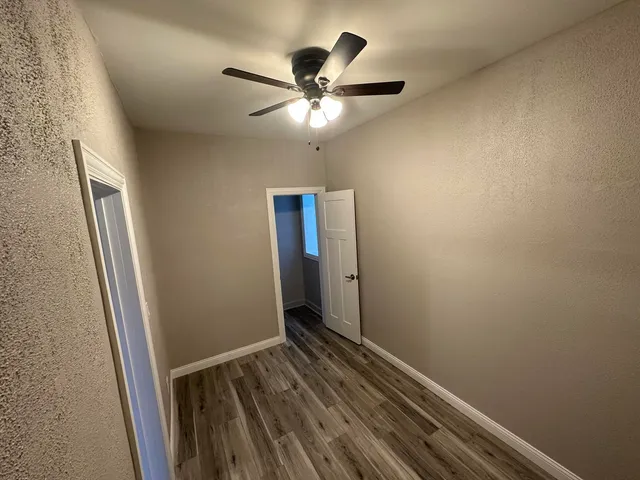 an empty room with wooden floor and a ceiling fan