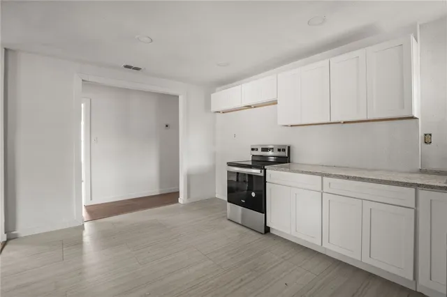 a kitchen with granite countertop white cabinets and black appliances