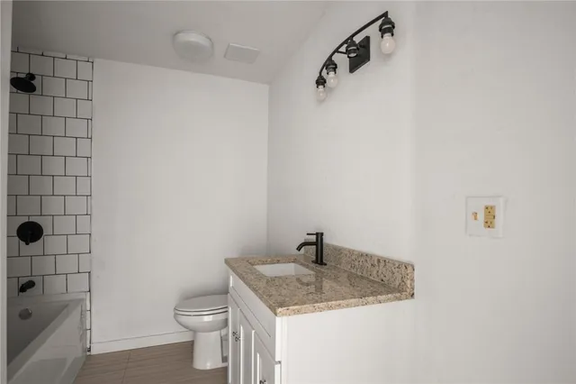 a bathroom with a granite countertop sink a toilet and shower