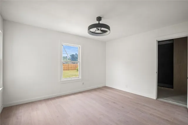 an empty room with a window and a ceiling fan