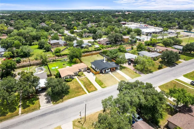 an aerial view of residential houses with outdoor space and trees