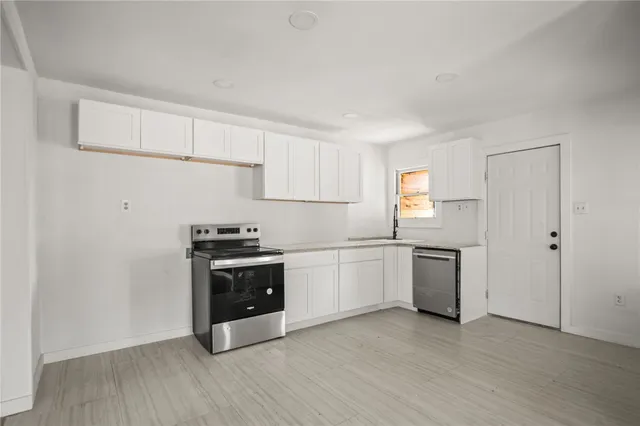 a kitchen with granite countertop white cabinets and stainless steel appliances
