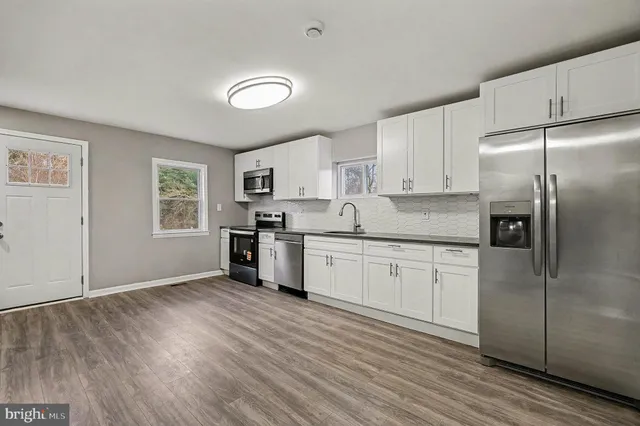 a kitchen with granite countertop a refrigerator and a stove top oven