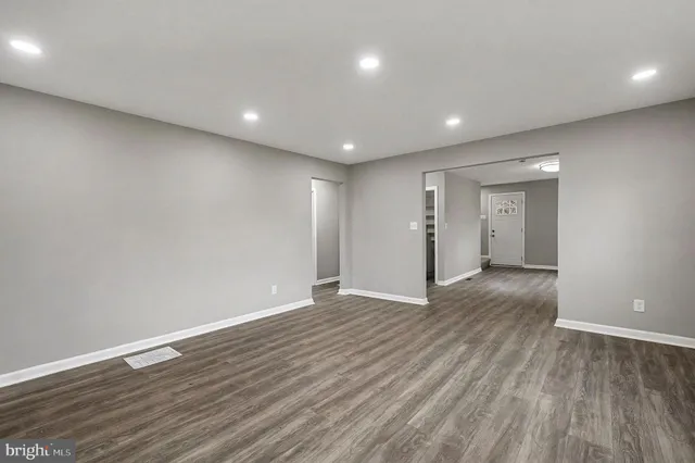 a view of an empty room with wooden floor and closet