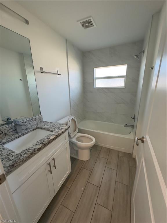 3707 38th Street Southwest Lehigh Acres, FL 33976 - Photo 11 of 16 Bathroom with vanity, shower combination, and wood finish floors