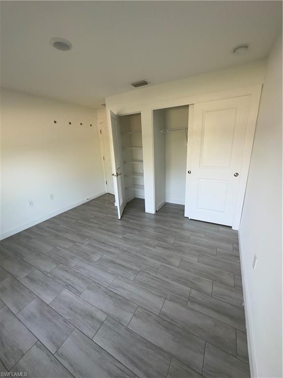 3707 38th Street Southwest Lehigh Acres, FL 33976 - Photo 12 of 16 Unfurnished bedroom featuring two closets and light wood finished floors