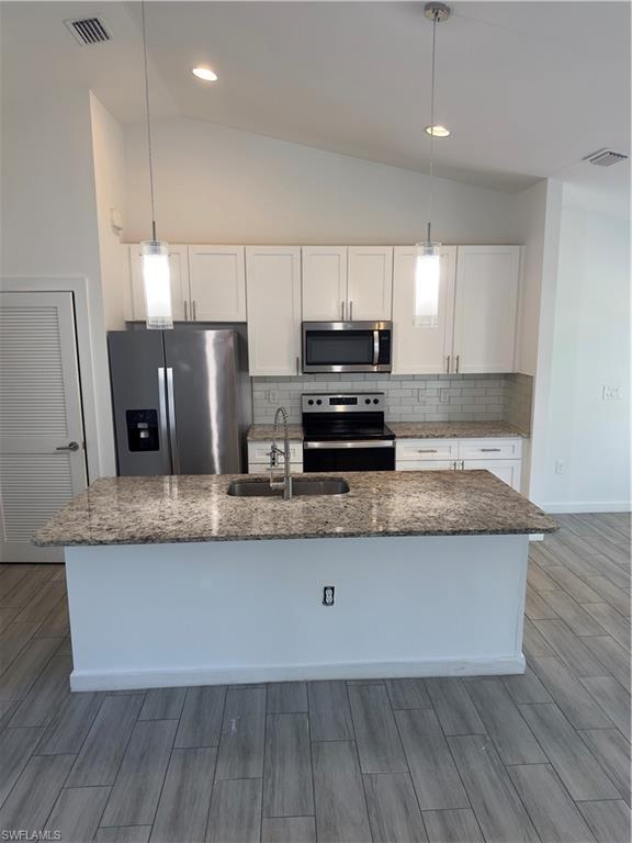 3707 38th Street Southwest Lehigh Acres, FL 33976 - Photo 5 of 16 Kitchen featuring stainless steel appliances, tasteful backsplash, white cabinets, dark stone counters, and lofted ceiling