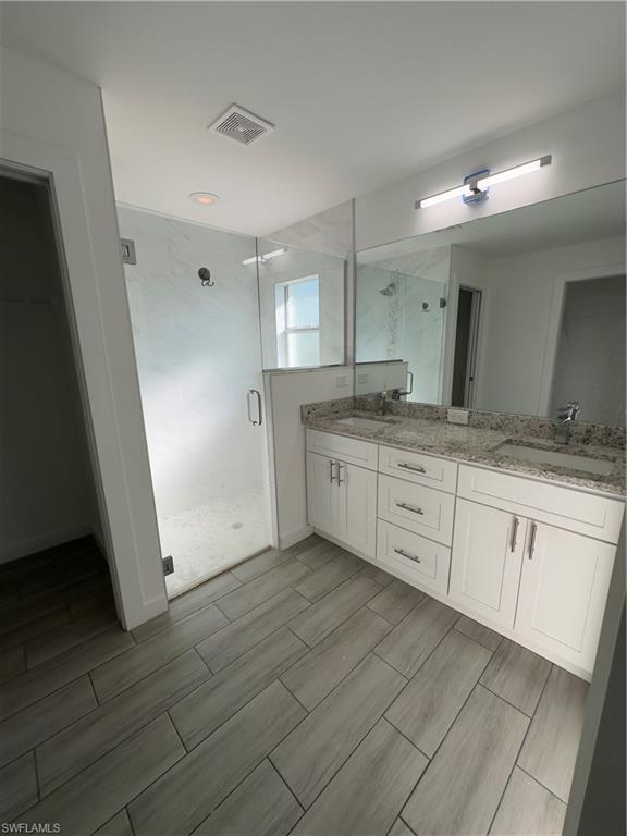 3707 38th Street Southwest Lehigh Acres, FL 33976 - Photo 8 of 16 Bathroom featuring a stall shower, double vanity, and wood tiled floors