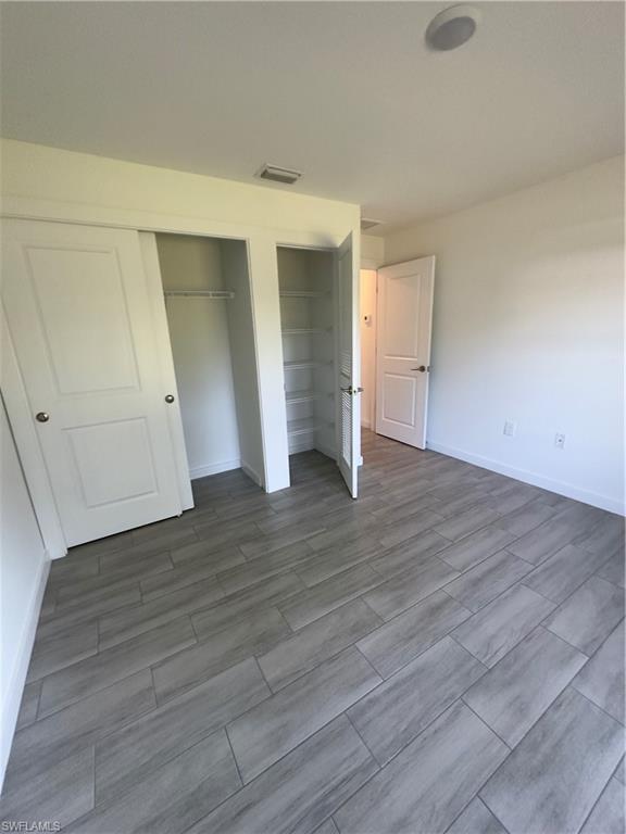 3707 38th Street Southwest Lehigh Acres, FL 33976 - Photo 10 of 16 Unfurnished bedroom with multiple closets and wood tiled floors