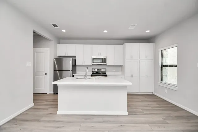 a kitchen with stainless steel appliances a sink a stove and cabinets