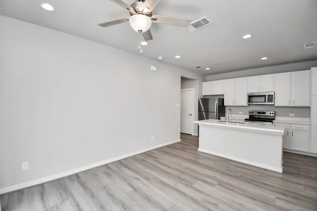 a view of kitchen island a sink wooden floor and a refrigerator