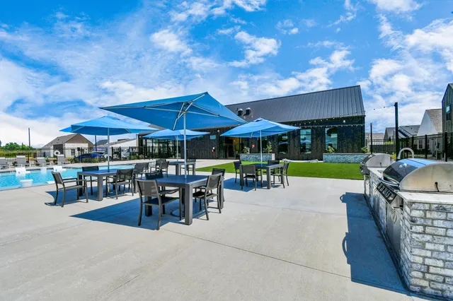 a swimming pool with outdoor seating and barbeque oven