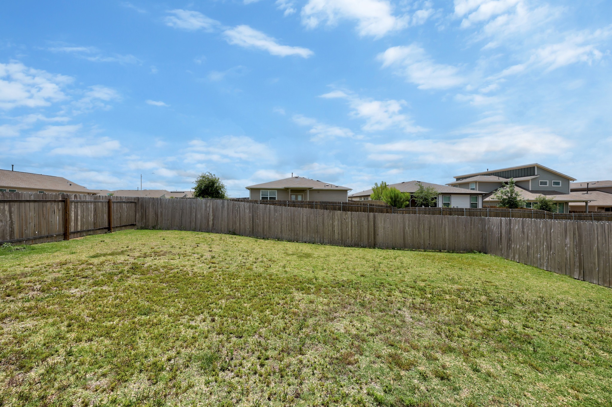 14121 Berning Road Manor, TX 78653 - Photo 24 of 27 A spacious backyard enclosed by a durable wooden fence, ready for personalized landscaping.