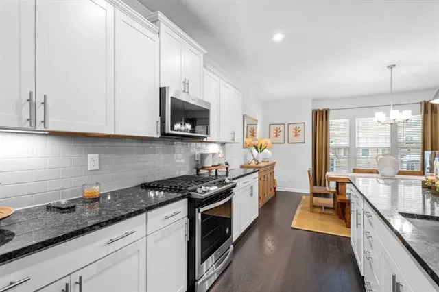 a kitchen with granite countertop a sink a stove top oven a counter space and cabinets