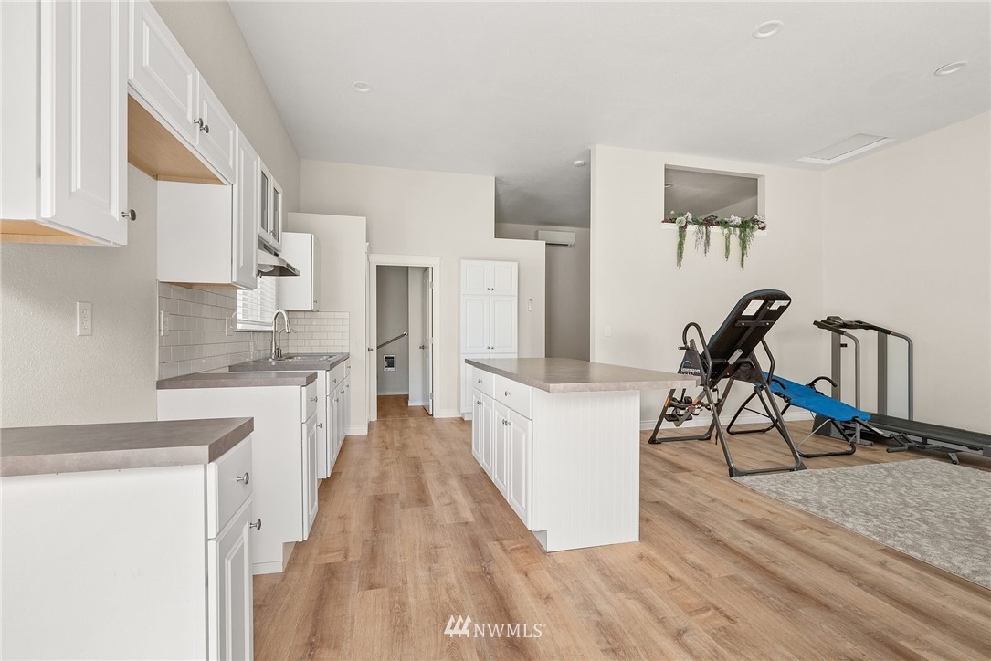 18622 Melon Street Southwest Rochester, WA 98579 - Photo 23 of 33 a kitchen with white cabinets and wooden floor
