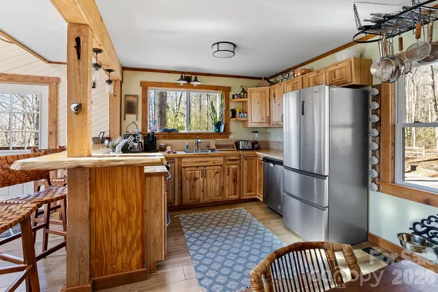 a kitchen with stainless steel appliances granite countertop a refrigerator a sink dishwasher a stove and white countertops with wooden floor