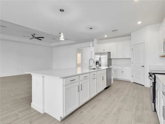 a kitchen with white cabinets a sink dishwasher and a stove with wooden floor