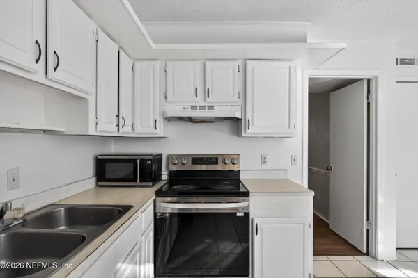 a kitchen with granite countertop white cabinets and stainless steel appliances