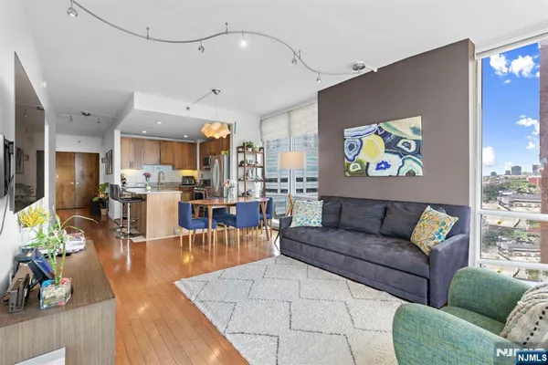 a living room with furniture kitchen view and a wooden floor