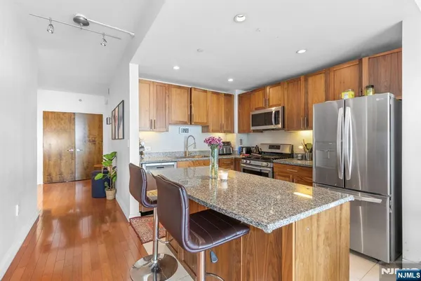 a kitchen with stainless steel appliances granite countertop a refrigerator a stove top oven a sink dishwasher and wooden cabinets