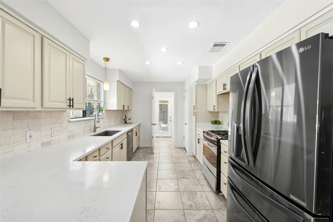 6906 Bayridge Terrace Austin, TX 78759 - Photo 10 of 35 a kitchen with granite countertop a refrigerator and a sink