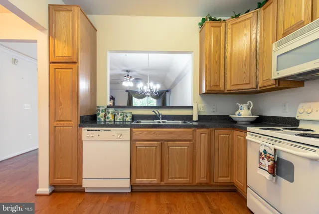 a kitchen with stainless steel appliances granite countertop a sink and cabinets with wooden floor