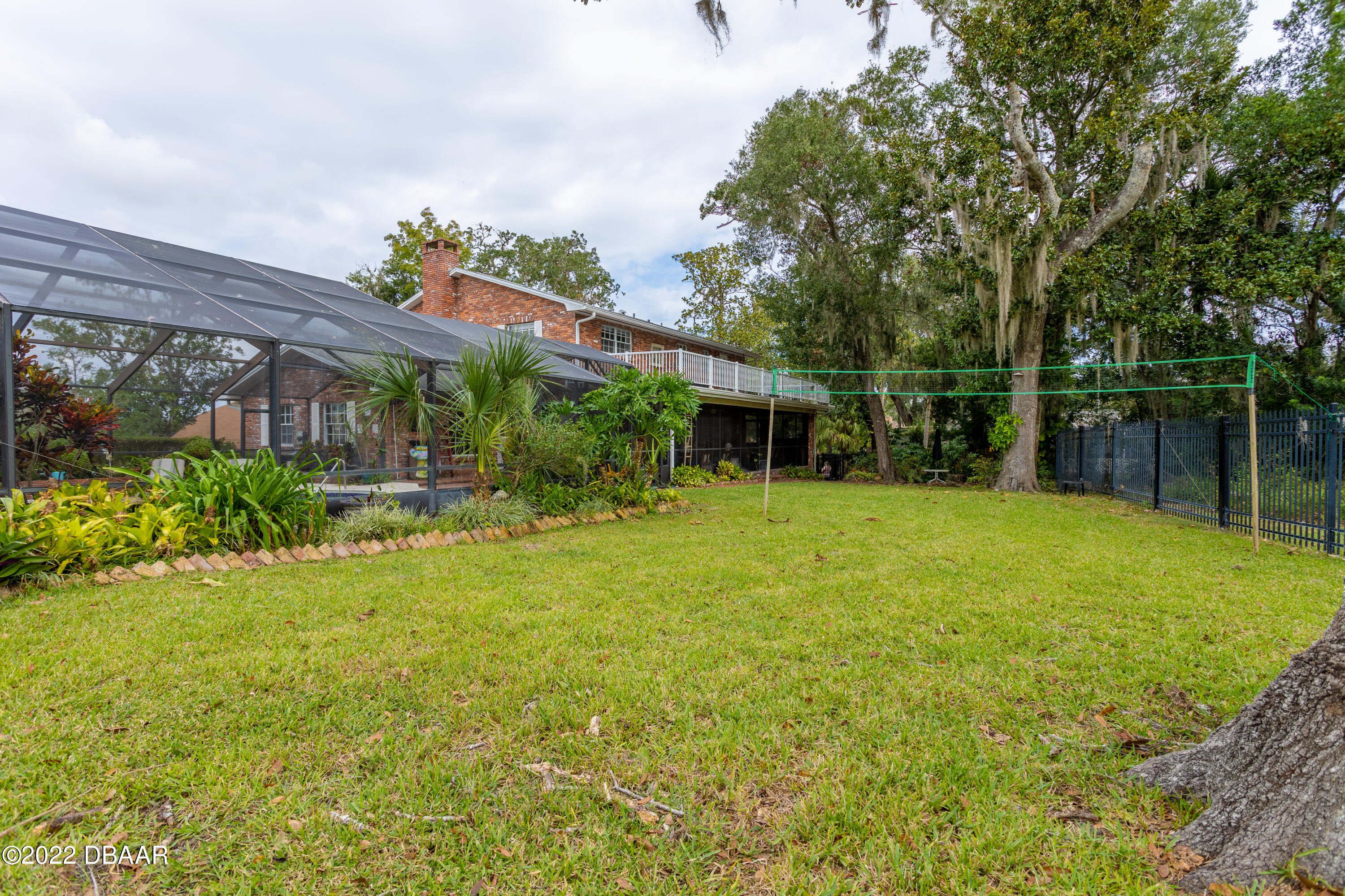 82 North St Andrews Drive Ormond Beach, FL 32174 - Photo 59 of 60 a backyard of a house with plants and wooden fence