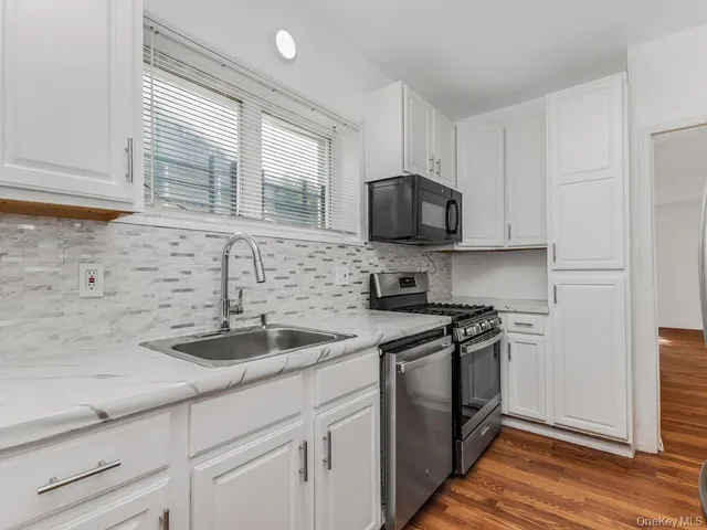 a kitchen with stainless steel appliances granite countertop a sink a stove and a microwave