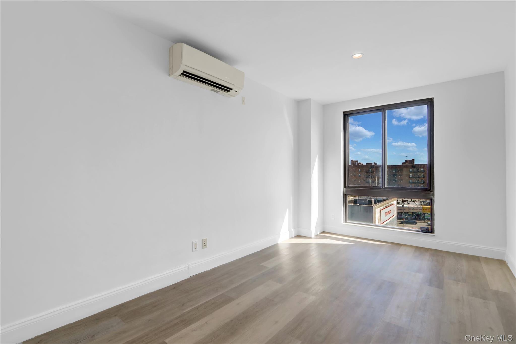 45-16 83rd Street, Unit E2J Queens, NY 11373 - Photo 9 of 15 an empty room with wooden floor and windows
