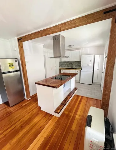 a living room with stainless steel appliances furniture stove and a wooden floor