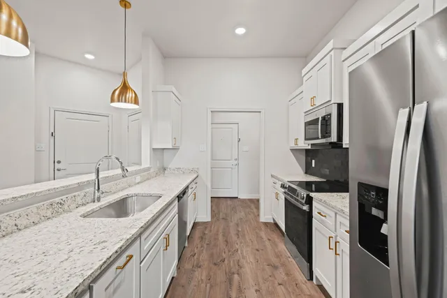 a kitchen with stainless steel appliances granite countertop a sink a stove and a wooden floors