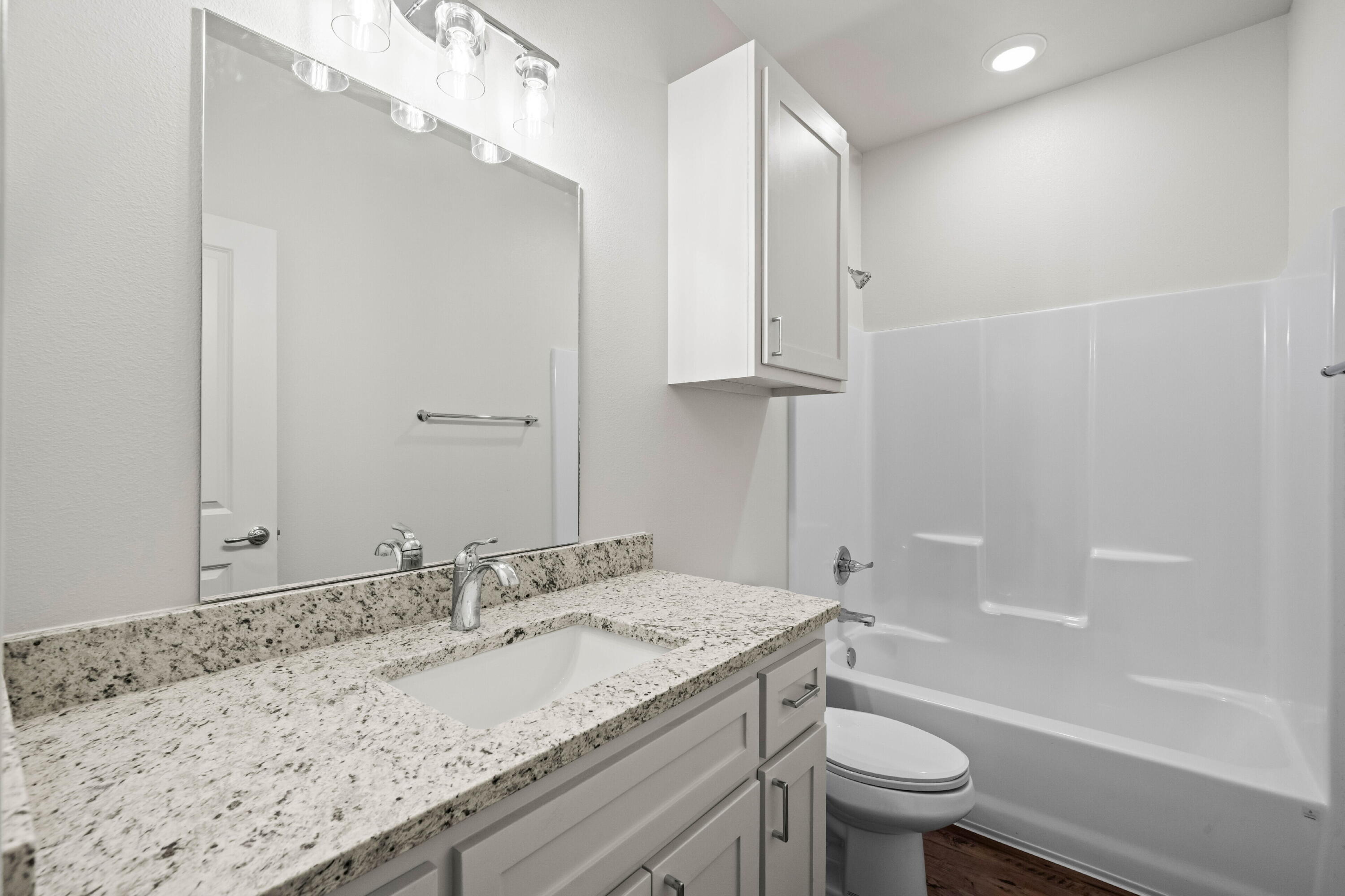 7014 40th Street, Unit A Lubbock, TX 79407 - Photo 9 of 19 a bathroom with a granite countertop sink a toilet and bathtub