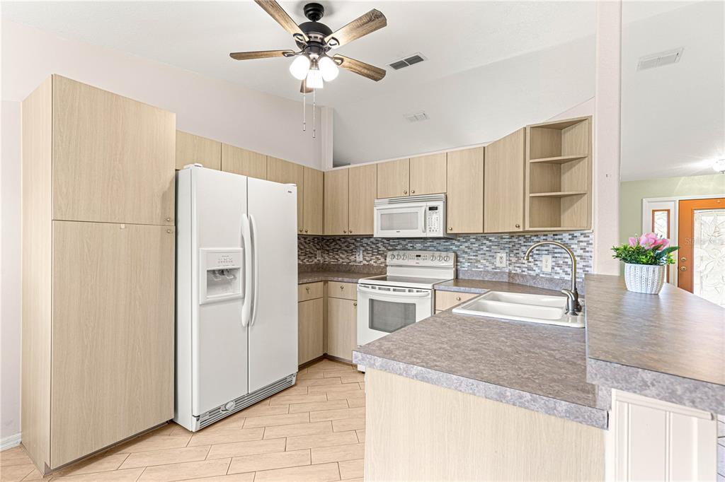 9958 Southwest 59th Circle Ocala, FL 34476 - Photo 12 of 45 a kitchen with stainless steel appliances granite countertop a refrigerator a sink dishwasher a stove with white cabinets and wooden floor