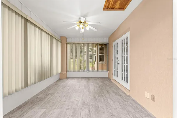 an empty room with wooden floor fan and windows