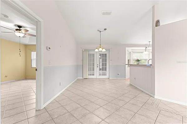 a view of an empty room with kitchen and window