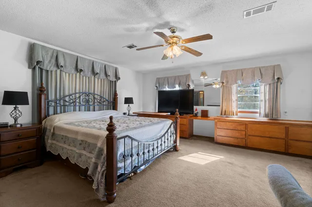 a bedroom with a bed a dresser and a chandelier