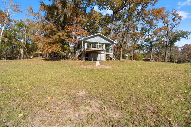 a backyard of a house with large trees and outdoor seating