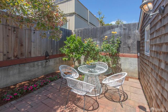 a backyard of a house with table and chairs potted plants