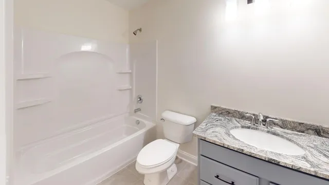 a bathroom with a granite countertop toilet a sink and a bathtub