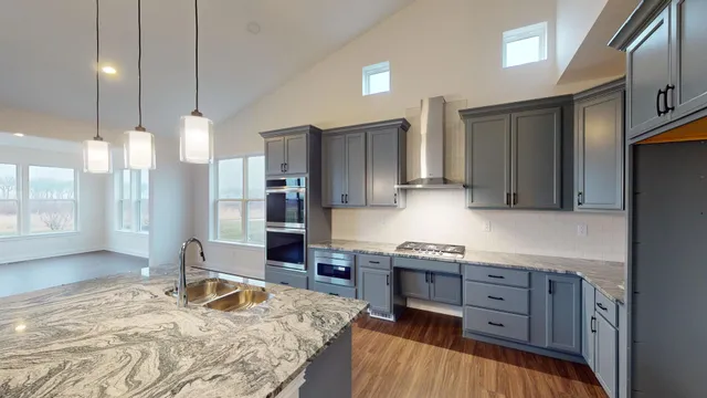 a kitchen with granite countertop a stove a sink and a refrigerator