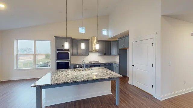 a kitchen with kitchen island granite countertop wooden cabinets a sink and a stove