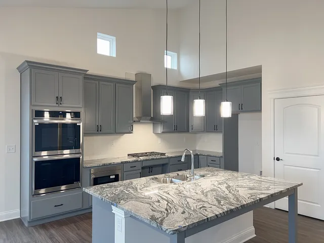 a kitchen with granite countertop a sink stove and refrigerator