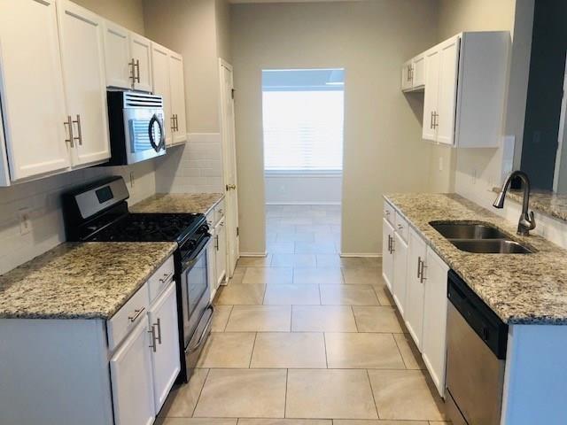 1608 Tristan Way Cedar Park, TX 78613 - Photo 2 of 18 Kitchen with appliances with stainless steel finishes, white cabinets, light stone countertops, decorative backsplash, and light tile patterned floors
