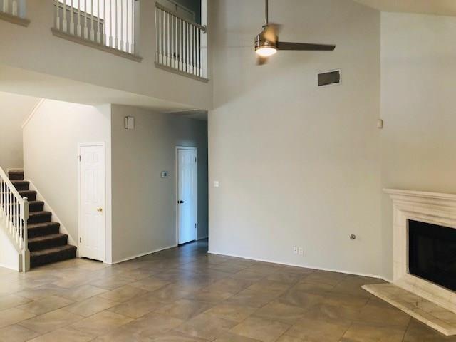1608 Tristan Way Cedar Park, TX 78613 - Photo 9 of 18 Unfurnished living room featuring a high ceiling, stairway, a fireplace with flush hearth, and ceiling fan