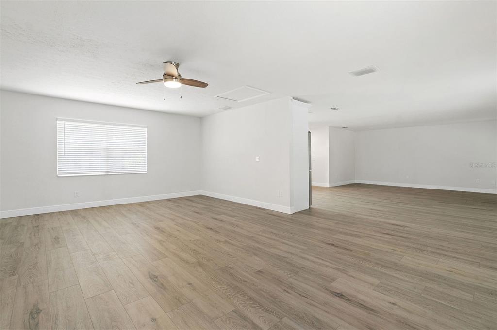 5207 Burr Place Seffner, FL 33584 - Photo 12 of 34 an empty room with wooden floor ceiling fan and windows