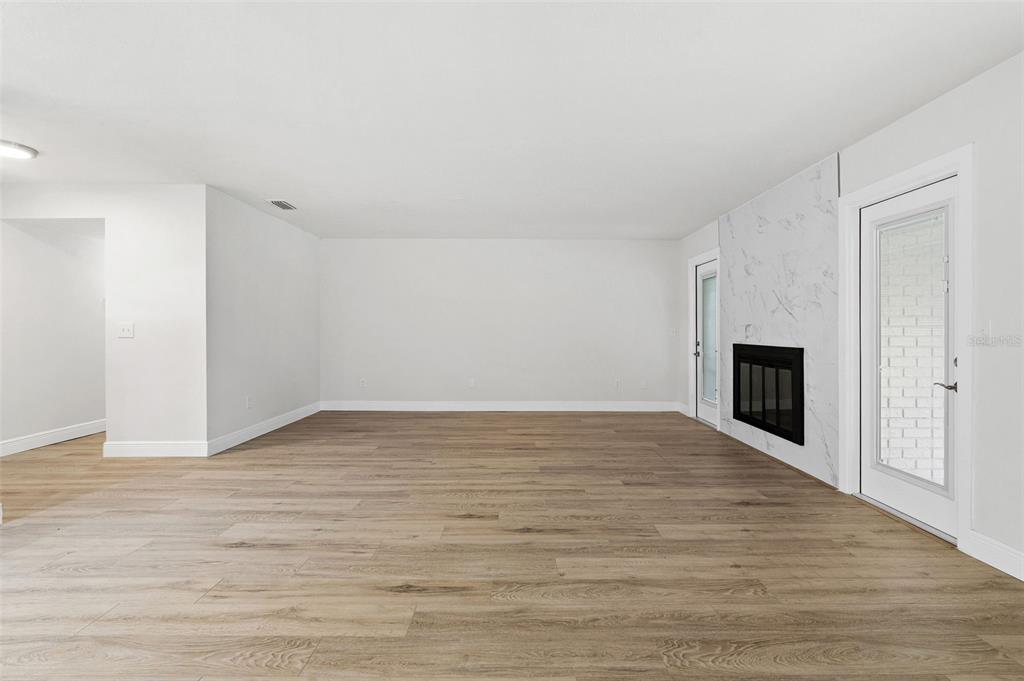 5207 Burr Place Seffner, FL 33584 - Photo 5 of 43 a view of empty room with wooden floor and fireplace