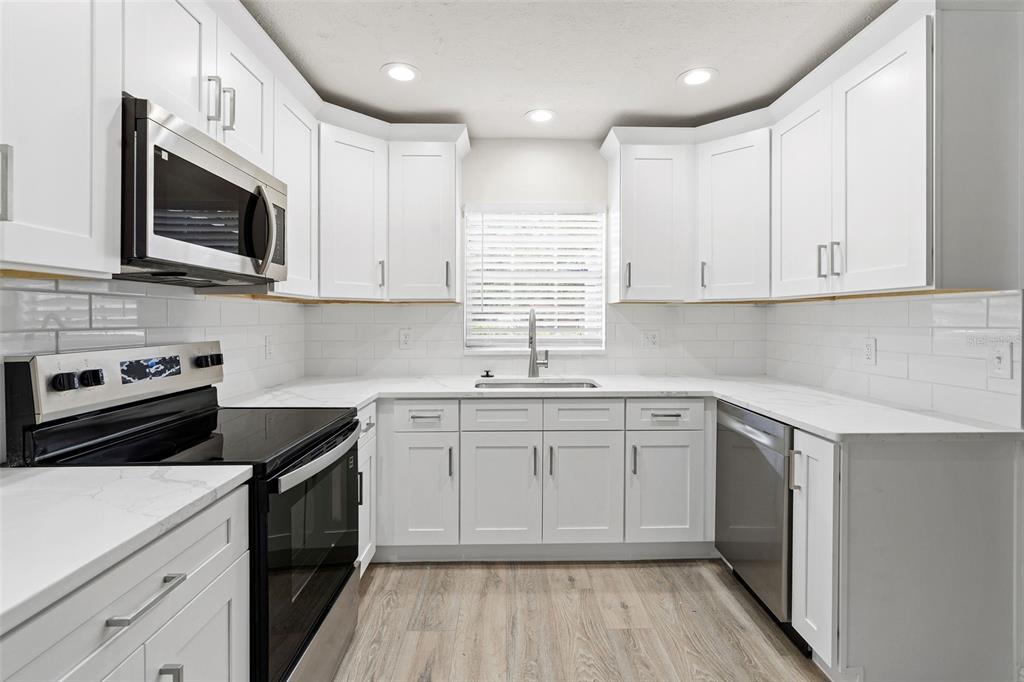 5207 Burr Place Seffner, FL 33584 - Photo 8 of 34 a kitchen with white cabinets stainless steel appliances and sink