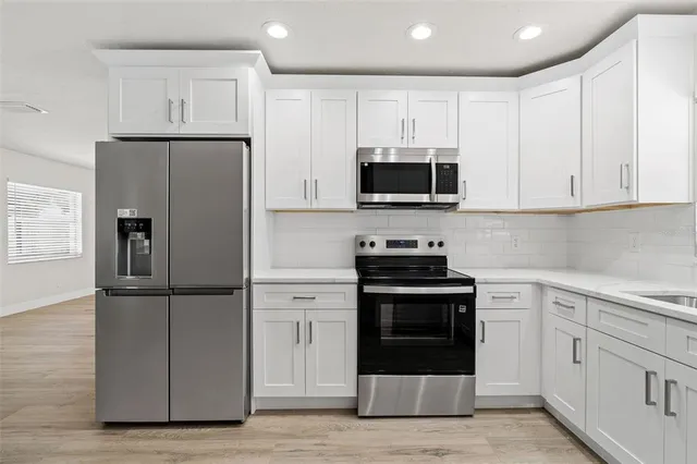 a kitchen with cabinets stainless steel appliances and wooden floor
