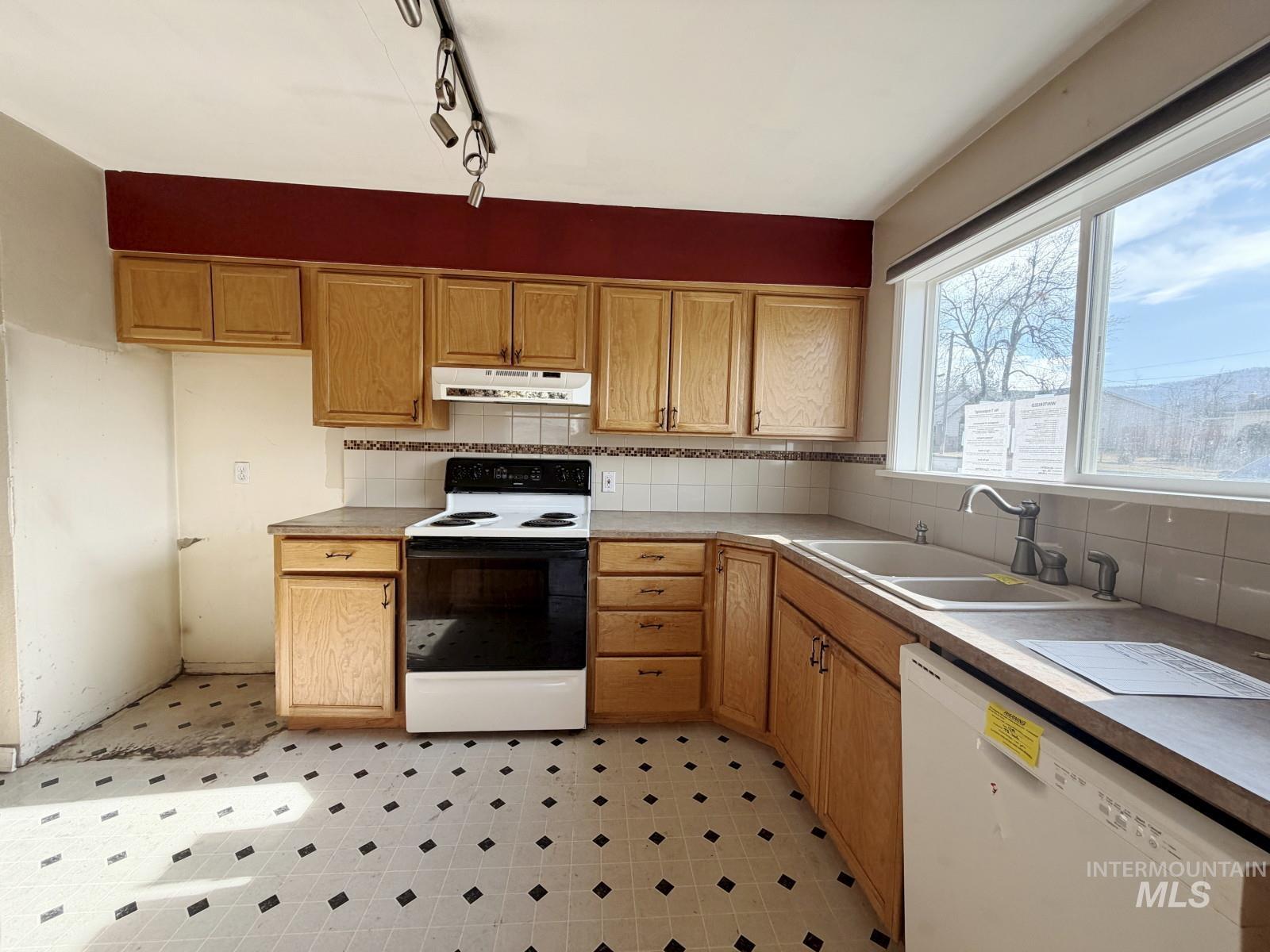 101 Southeast 7th Street Grangeville, ID 83530 - Photo 8 of 23 Kitchen with white appliances, tasteful backsplash, light floors, and track lighting